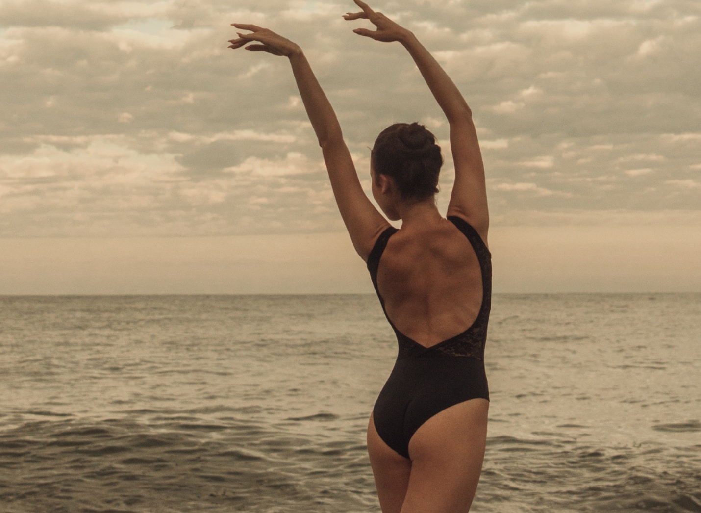 Photo stylisee d une femme a la plage faisant du sport en levant les bras en haut epilation laser | Maison abeille esthetique Paris